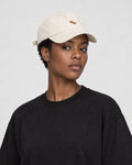 Woman wearing the cream corgi baseball cap with a black tee, three-quarter view