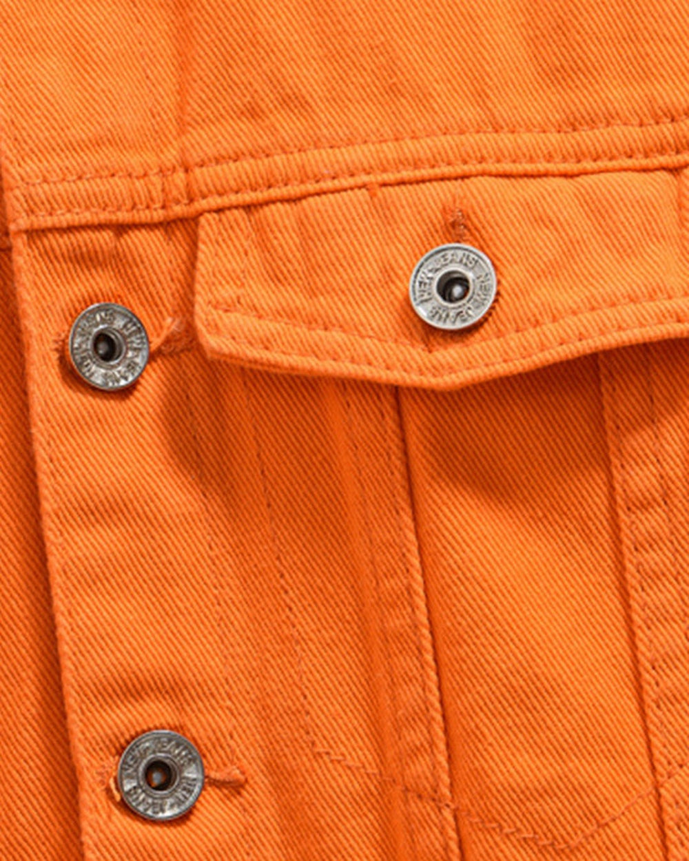 Close-up of a buttoned flap chest pocket on the orange denim