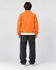 Model wearing the orange denim trucker jacket, back view