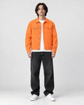 Model wearing the orange denim trucker jacket over a white tee, front view