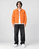 Model wearing the orange denim trucker jacket over a white tee, front view