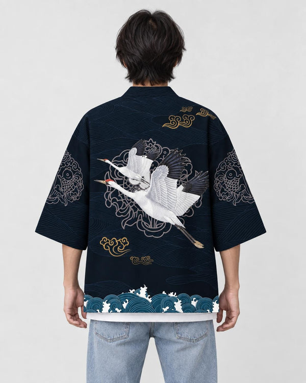 Man seen from behind in the dark navy haori with two white cranes in flight and a teal wave band, over a white tee