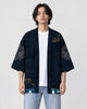 Man in the open dark navy haori with fish-scale medallions on the sleeves, a white tee and light jeans, front view