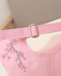 Close-up of the ring-buckle strap and the plum blossom branch embroidered on the back of the pink cap