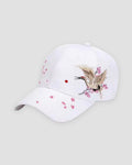 White baseball cap with a crane in flight embroidered over pink plum blossoms on the side of the crown