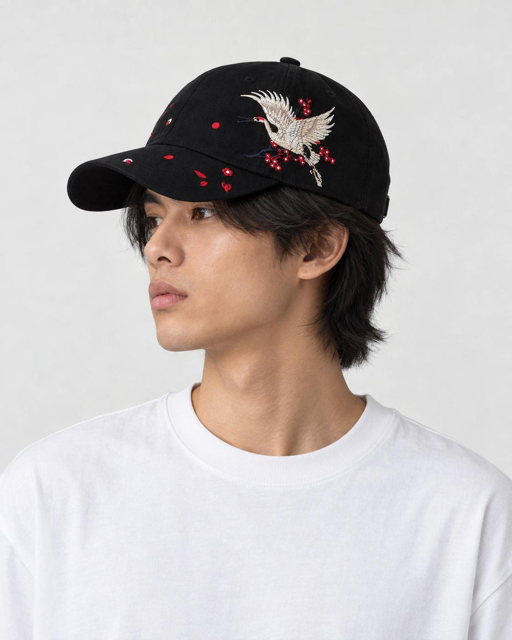 Model wearing the black crane embroidered baseball cap with a white tee, side view