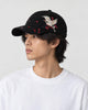 Model wearing the black crane embroidered baseball cap with a white tee, side view