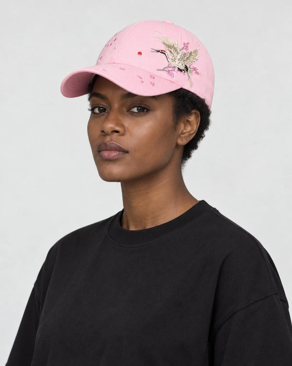 Model wearing the pink crane embroidered baseball cap with a black tee, three-quarter view
