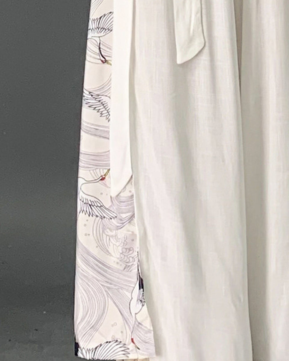 Close-up of the pale gray crane and wave side panel and the tie sash on the white wide-leg pants