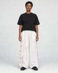 Model wearing the white wide-leg pants with pale gray crane and wave side panels and a black tee, front view