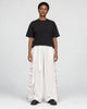 Model wearing the white wide-leg pants with pale gray crane and wave side panels and a black tee, front view