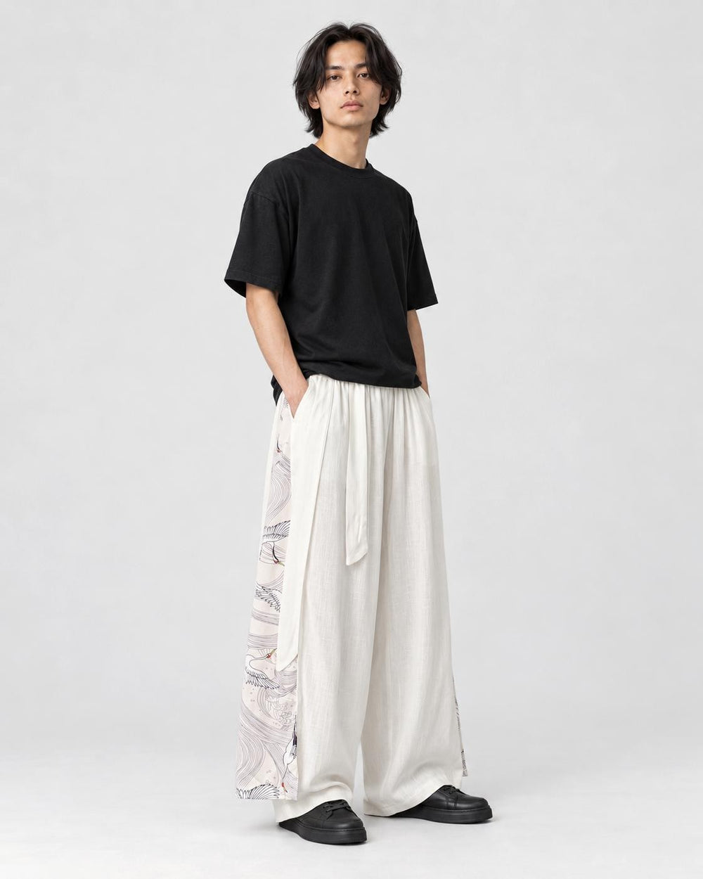 Model wearing the white wide-leg pants with crane and wave side panels, three-quarter view