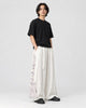 Model wearing the white wide-leg pants with crane and wave side panels, three-quarter view