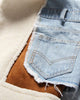 Close-up of the raw-edged denim pocket over the tan suede-look panel