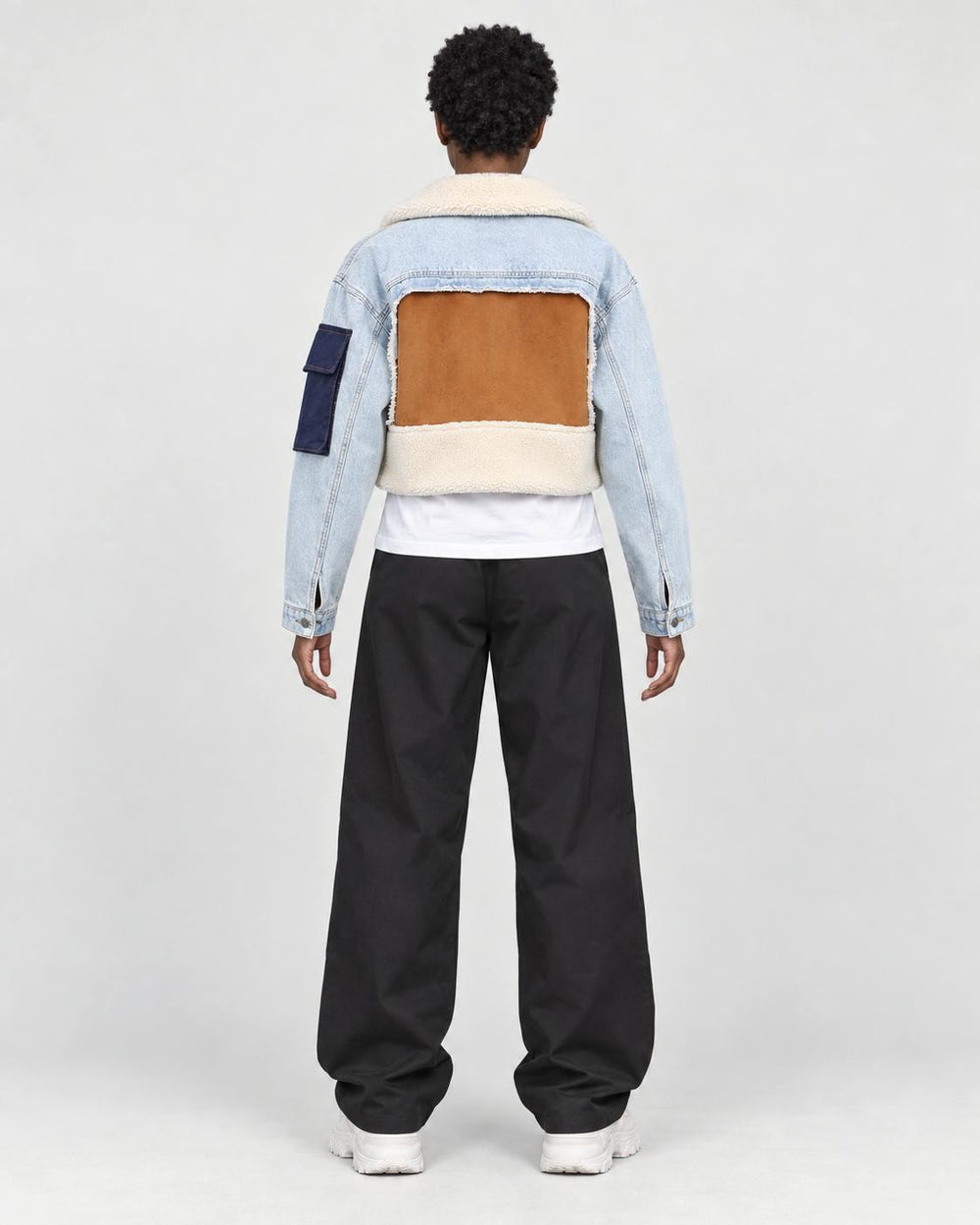 Model wearing the light blue cropped jacket, back view of the tan panel and fleece hem