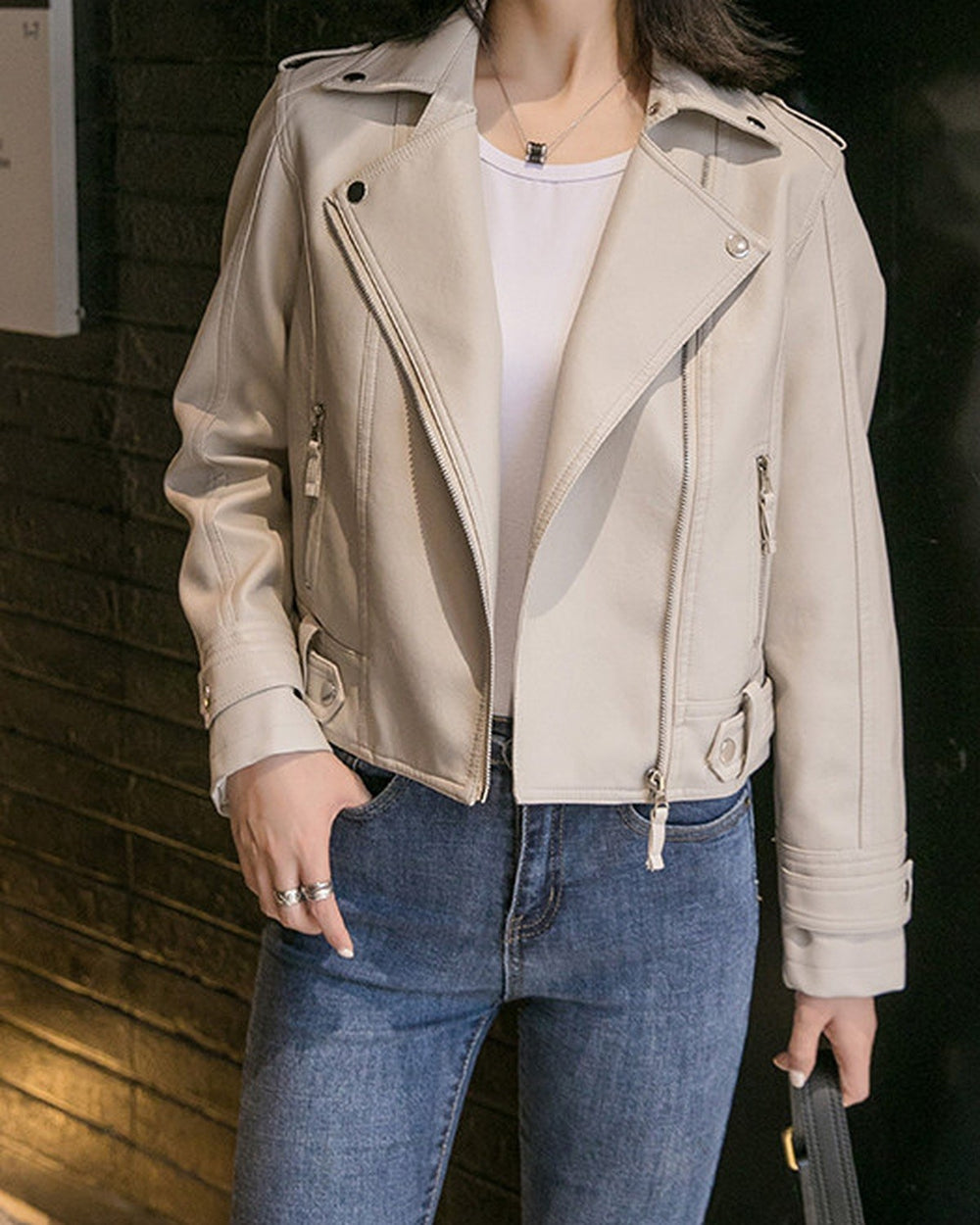Close-up of the zip pockets and hem tabs on the cream moto jacket