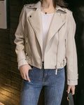 Close-up of the zip pockets and hem tabs on the cream moto jacket