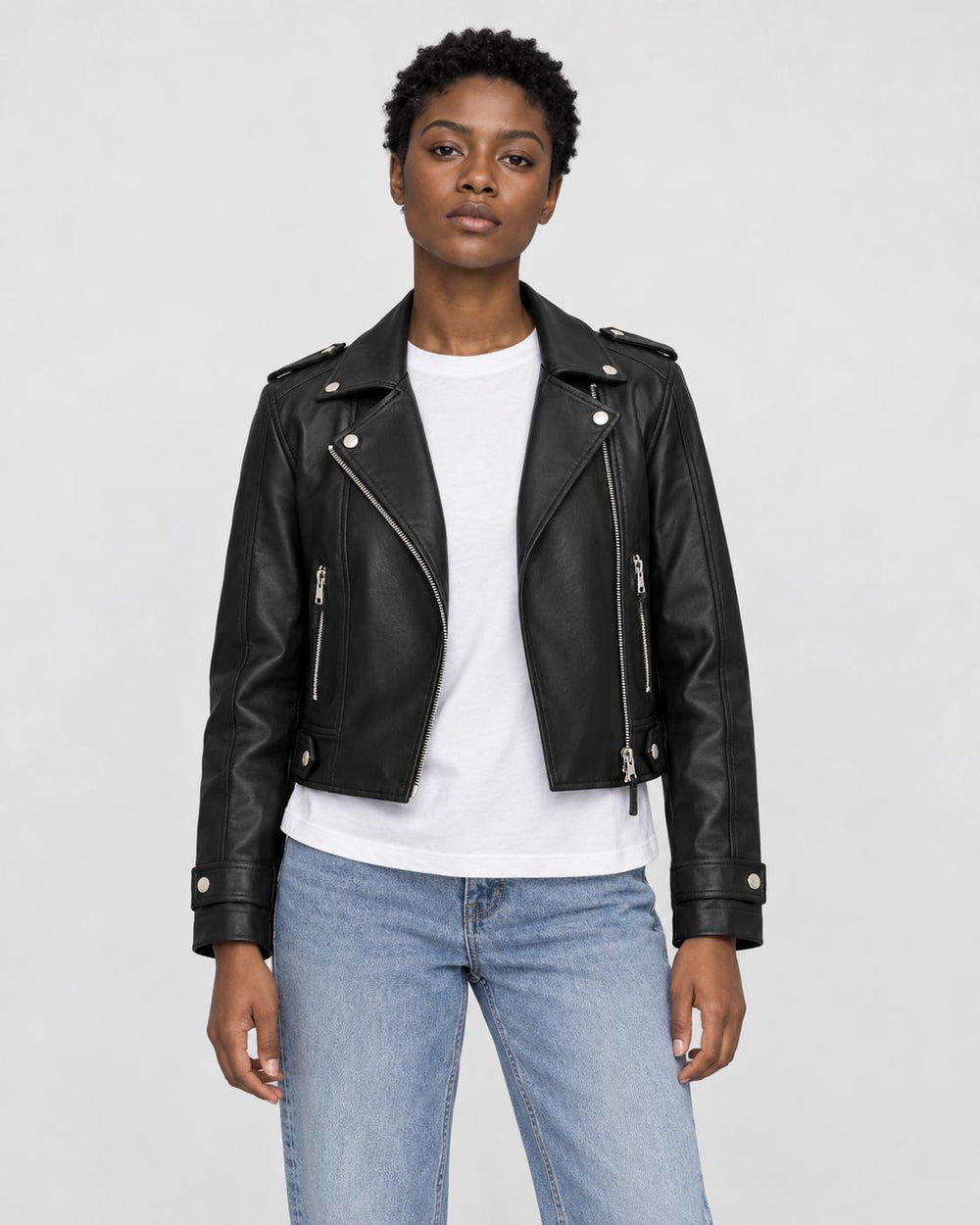 Model wearing the black cropped moto jacket open over a white tee, front view