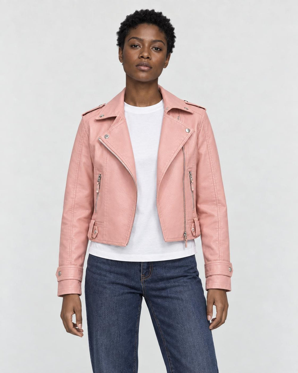 Model wearing the pink cropped moto jacket open over a white tee, front view