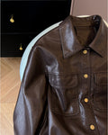 Close-up of the collar, flap pockets and gold snaps on the brown jacket