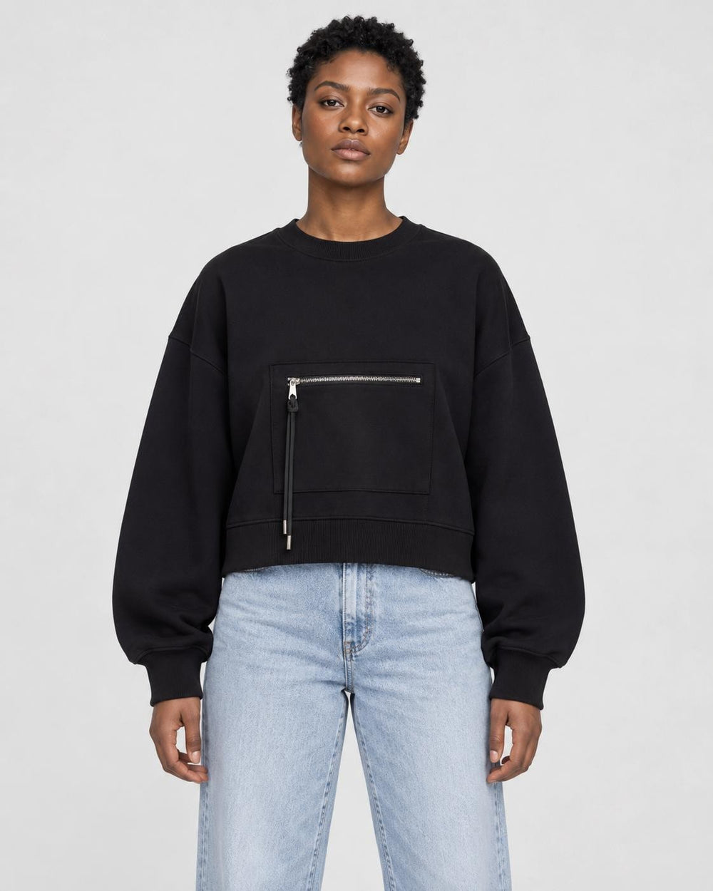 Model wearing the black cropped sweatshirt with light-wash jeans, front view