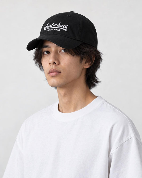 Model wearing the black cursive script dad cap with a white tee, three-quarter view