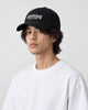 Model wearing the black cursive script dad cap with a white tee, three-quarter view