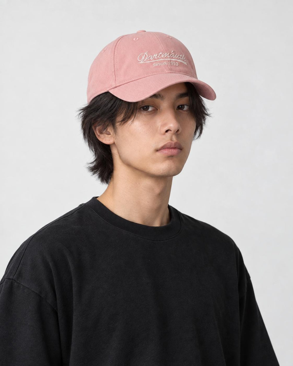Model wearing the pink cursive script dad cap with a black tee, three-quarter view