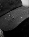 Close-up of the stitched and frayed brim of the black cap