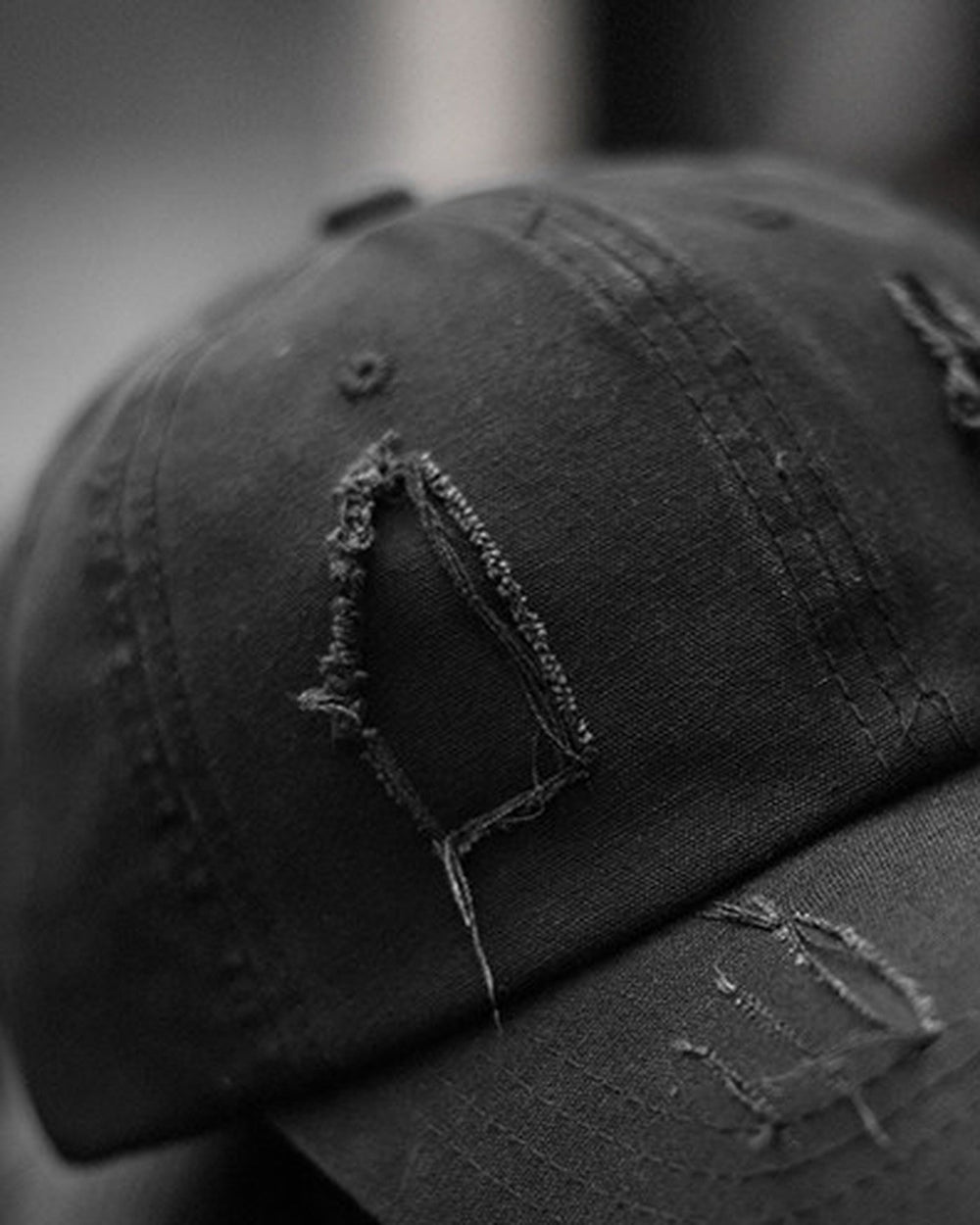 Close-up of the tall frayed hole on the crown of the black cap