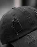 Close-up of the tall frayed hole on the crown of the black cap
