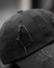 Close-up of the tall frayed hole on the crown of the black cap