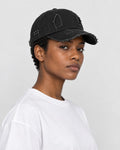 Model wearing the black distressed baseball cap with a white tee, side view