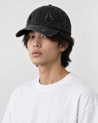 Model wearing the black distressed baseball cap with a white tee, three-quarter view