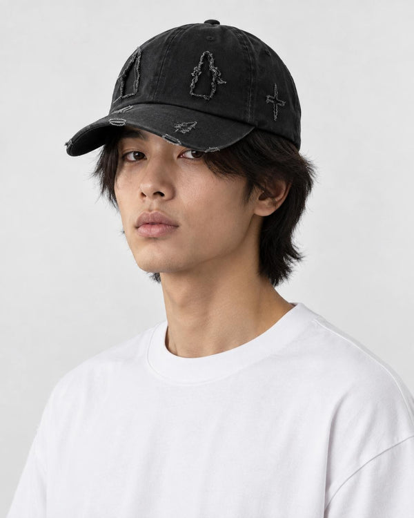 Model wearing the black distressed baseball cap with a white tee, three-quarter view