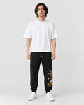 Model wearing the black dragon embroidered jogger pants with a white tee, front view