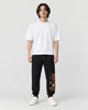 Model wearing the black dragon embroidered jogger pants with a white tee, front view