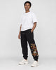 Model wearing the black dragon embroidered jogger pants with chunky sneakers, three-quarter view