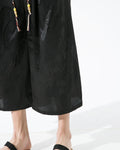 Close-up of the glossy black dragon-and-cloud jacquard and the drawcord tassels on the pants