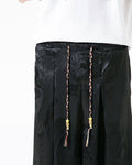 Close-up of the elastic waist, front pleats and braided drawcord with yellow beads and tassels on the black pants