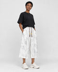 Model wearing the white dragon jacquard cropped wide-leg pants with a black tee and white sneakers, three-quarter view