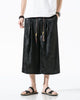 Black dragon jacquard wide-leg pants with front pleats and a beaded, tasseled drawcord, worn with a white tee
