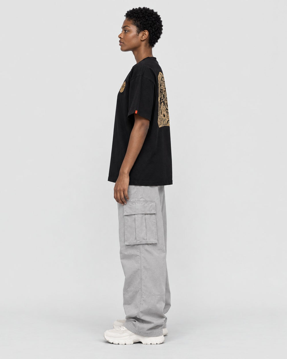 Model wearing the black dragon seal T-shirt with grey cargo pants, side view