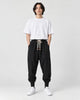 Model wearing the black drop-crotch harem pants with a white tee, front view