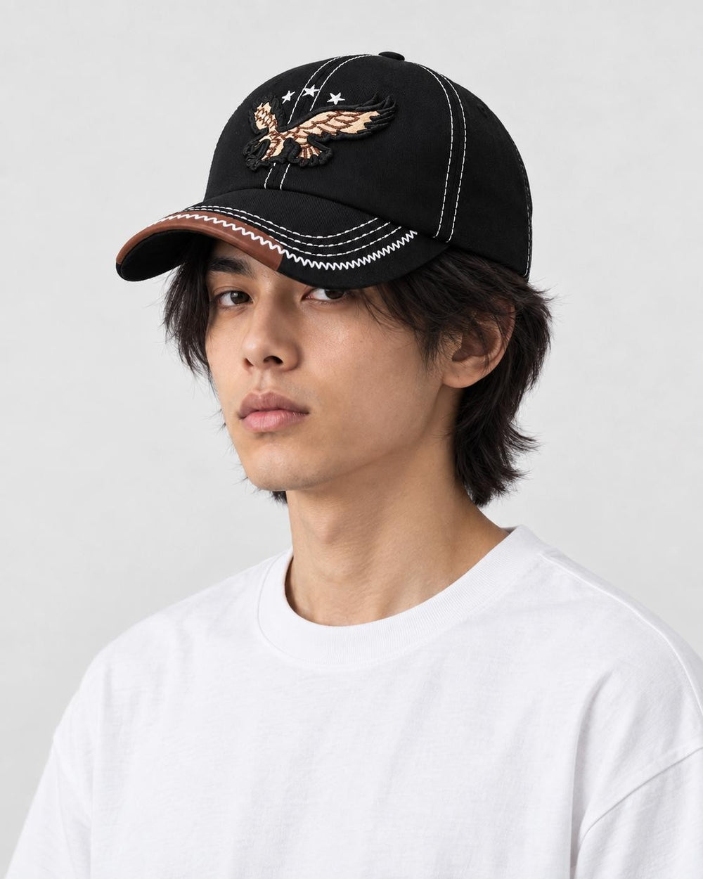 Model wearing the black eagle embroidered cap, three-quarter view