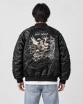 Model seen from behind in the black padded bomber jacket with a cream eagle and map embroidery, a white tee and light jeans