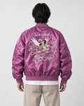 Model seen from behind in the purple padded bomber jacket with a cream eagle and map embroidery and stone trousers