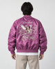 Model seen from behind in the purple padded bomber jacket with a cream eagle and map embroidery and stone trousers