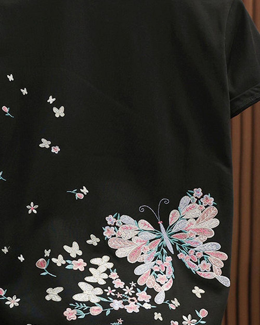 Close-up of the large embroidered butterfly and scattered blossoms on the black tee