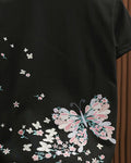 Close-up of the large embroidered butterfly and scattered blossoms on the black tee